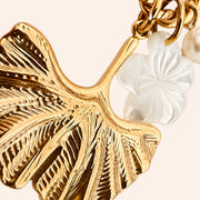 Ma boutique Ginkgo interchangeable earring charm featuring a textured gold ginkgo leaf and a white pearlescent flower.