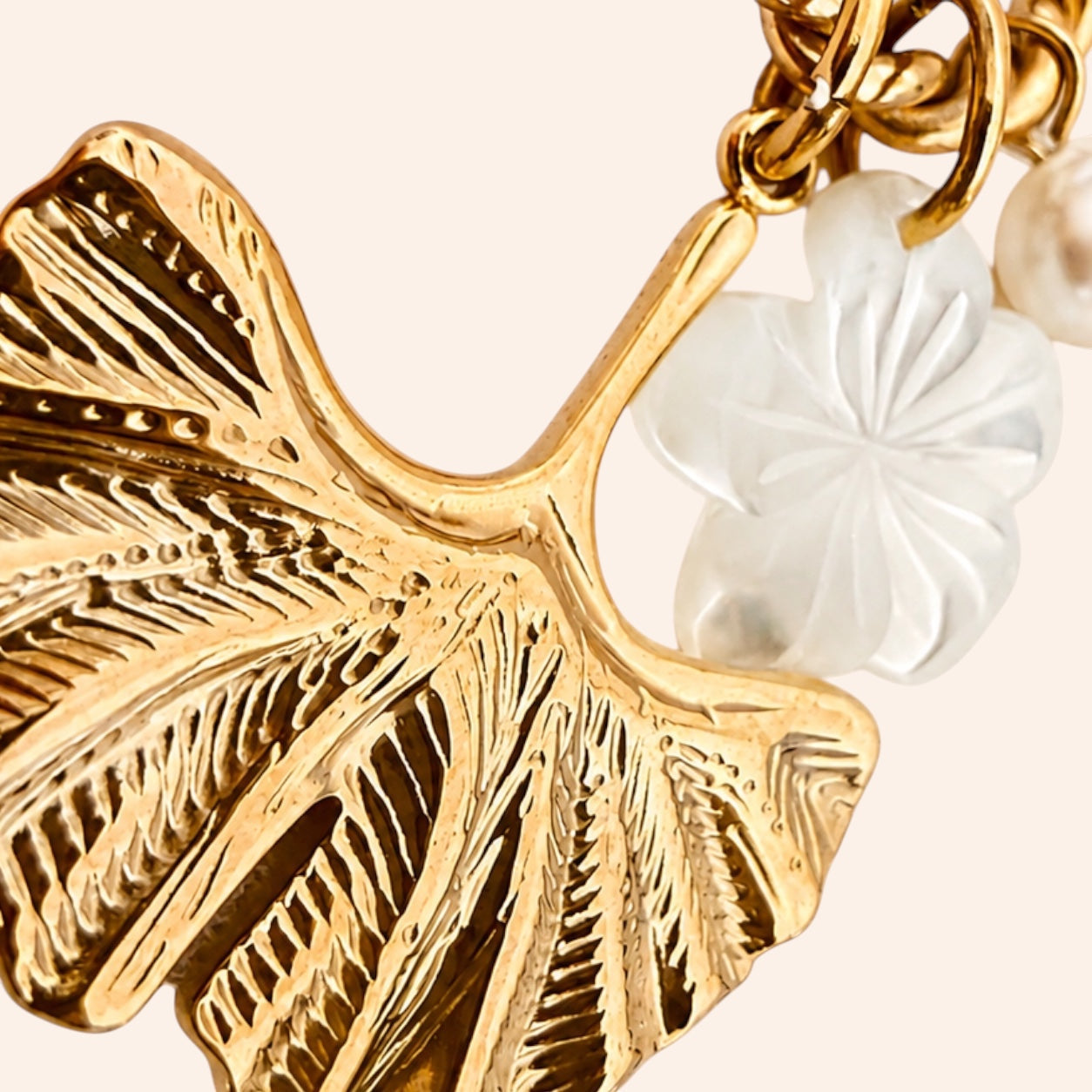 Ma boutique Ginkgo interchangeable earring charm featuring a textured gold ginkgo leaf and a white pearlescent flower.