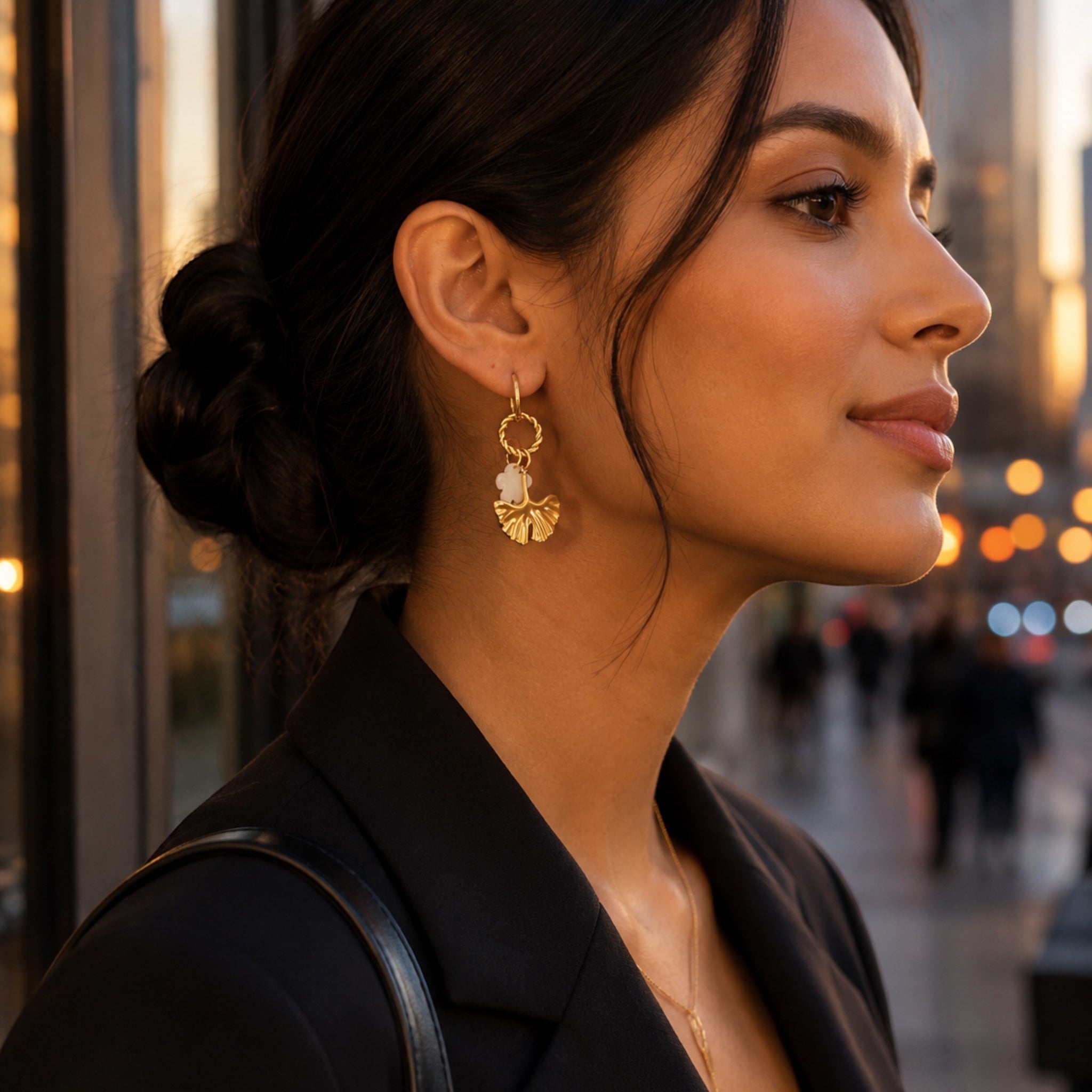 Ma boutique Ginkgo interchangeable gold and pearlescent leaf earring charm worn by a woman in a city setting