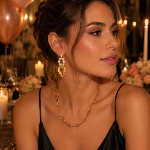 Ma boutique Amore interchangeable earring charm featuring a gold heart and pearl accents worn by a woman at dinner