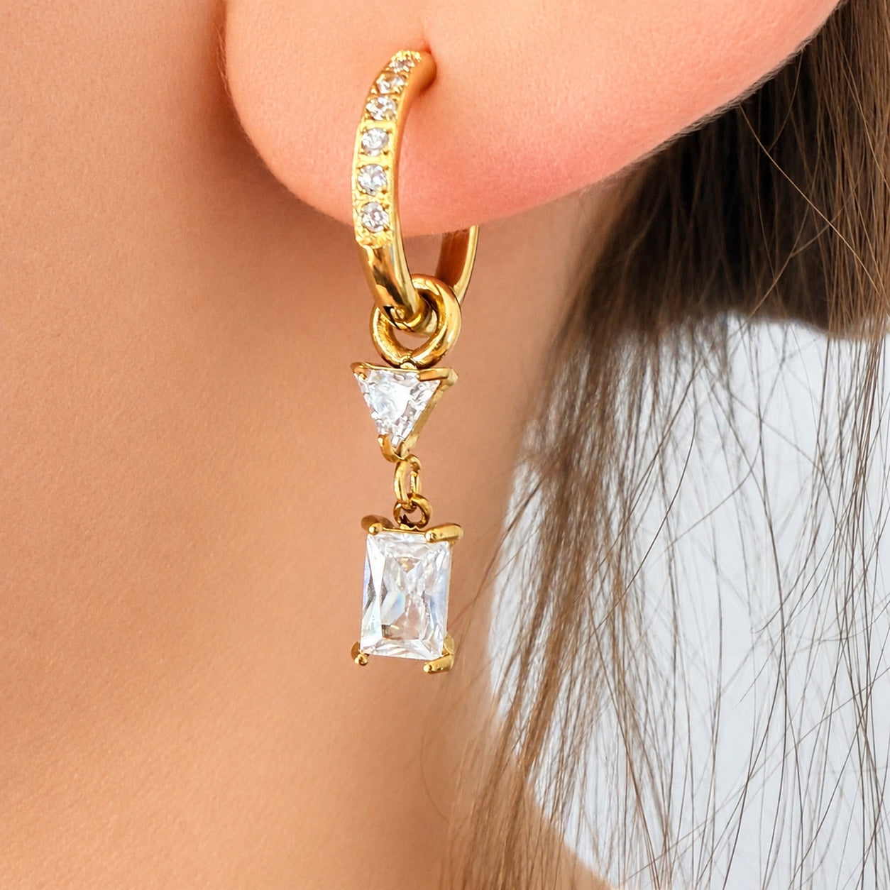 Ma boutique Minuit interchangeable gold earring charm with a clear rectangular stone worn on a crystal hoop earring